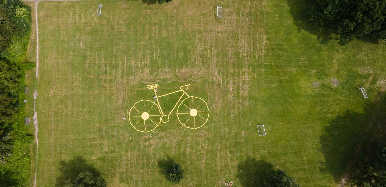 Gul cykel bygget i græsset - billede taget med luftfoto